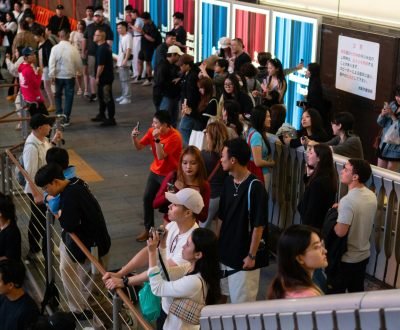 A vibrant urban scene with a diverse crowd of people gathered outdoors.